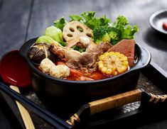 a black bowl filled with meat and vegetables