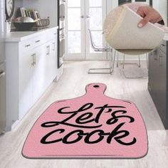 a pink kitchen mat with the words let's cook on it in black lettering