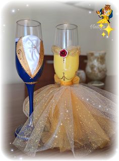 two wine glasses decorated like princess and prince's outfits on top of a table