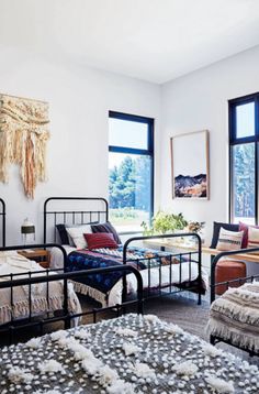 two beds in a room with large windows and rugs on the floor next to them