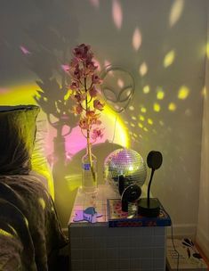 a bed room with a mirror ball and a flower on the nightstand next to it