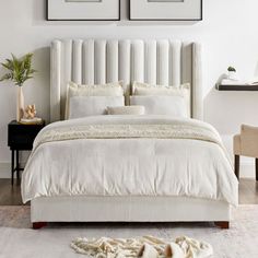 a white bed with two framed pictures above it