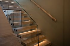 a set of stairs with glass railing and wooden handrails