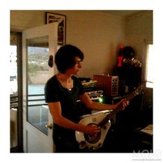 a woman playing an electric guitar in her home