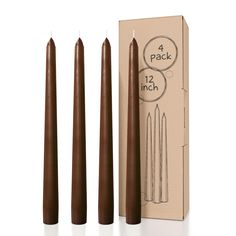 three brown candles sitting next to each other in front of a cardboard box and packaging