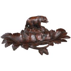 a wooden bear figurine sitting on top of an acorn shaped leafy base