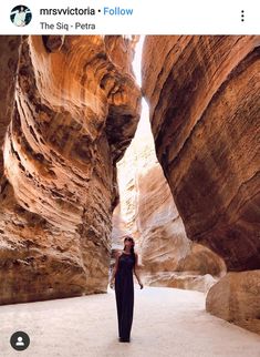 a woman standing in the middle of a narrow canyon