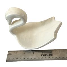 a white swan figurine sitting next to a ruler