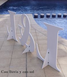 two white metal letters sitting next to a swimming pool