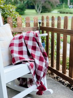 a white rocking chair with a red and white checkered blanket sitting on top of it