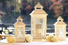 three white lanterns sitting on top of a table