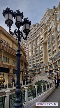 a lamp post in the middle of a shopping area with people walking around and buildings behind it