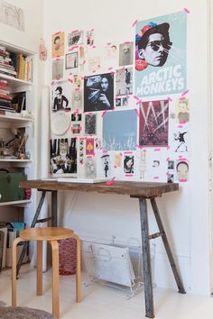 a wooden table sitting in front of a white wall covered with pictures and magnets