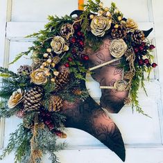 a christmas wreath hanging on the side of a door with pine cones and evergreens