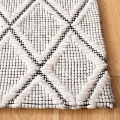 a white and black area rug on a wooden floor with wood floors in the background