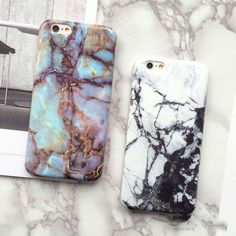 two cell phones sitting next to each other on top of a marble countertop in front of a wooden frame