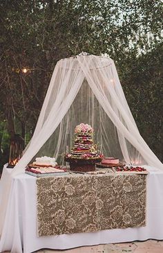 a table with a cake on top of it and a white net hanging over it