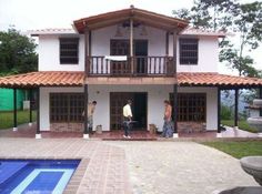 two men are standing in front of a house with a swimming pool and fence around it