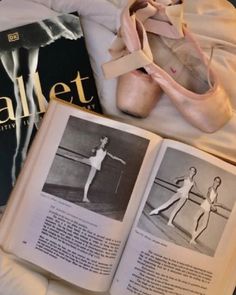 an open book sitting on top of a bed next to ballet shoes and ballerinas