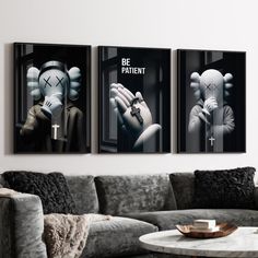 three posters on the wall above a couch in a living room with a coffee table