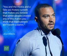 a man standing in front of a microphone with a quote on the screen behind him