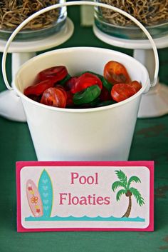 a bucket filled with gummy bears sitting on top of a table next to a sign that says pool floaties