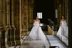 two women in white dresses are walking down the aisle