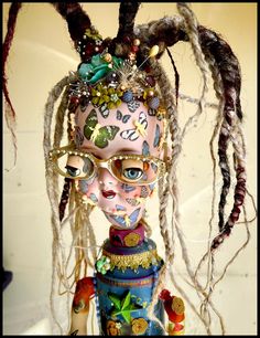 a doll with dreadlocks and eyeglasses on it's head is dressed up