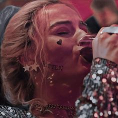 a woman drinking from a wine glass with her face covered in confetti and stars