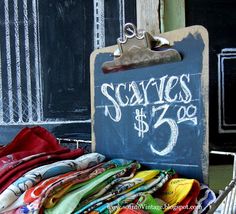 there is a sign that says scarves $ 5 99 on it and some folded shirts