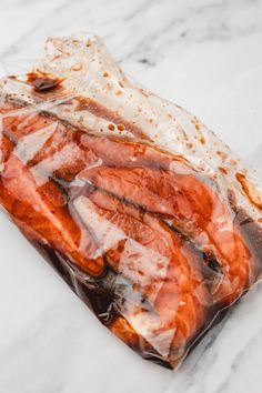 some kind of food wrapped in plastic on top of a marble countertop with lots of brown and white stuff