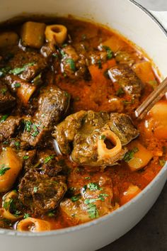 a pot filled with meat and pasta in tomato sauce, garnished with parsley