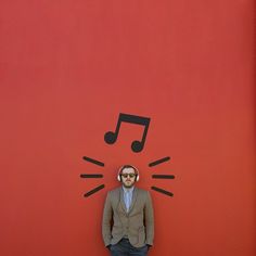 a man standing in front of a red wall with a musical note drawn on it