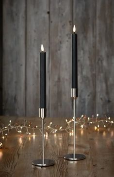 two black candles sitting on top of a wooden table