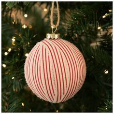 a red and white striped ornament hanging from a christmas tree