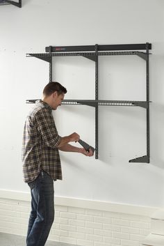 a man is using a drill to fix a wall mounted shelving unit