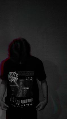 a man standing in front of a wall with his back turned to the camera and wearing a black shirt