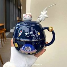 a person holding a space themed tea pot