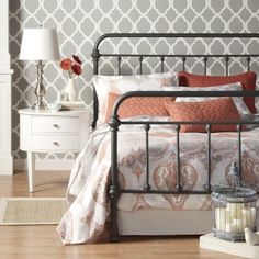 a bed with orange and white pillows in a bedroom next to a lamp on a table