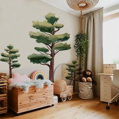 a child's bedroom with painted trees on the wall and wooden furniture in the foreground