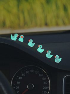 there are five ducks on the dashboard of this car, and one is green with red beaks