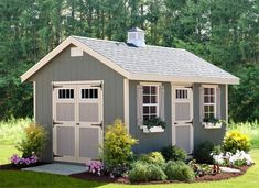 a small shed with windows and flowers in the front yard, next to some trees