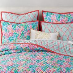 a bed with colorful bedspreads and pillows