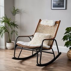 a rocking chair with white fur on it in a living room next to a potted plant