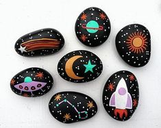 painted rocks are arranged in the shape of rockets and planets, with stars on them