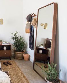 a bedroom with a mirror, dresser and plants