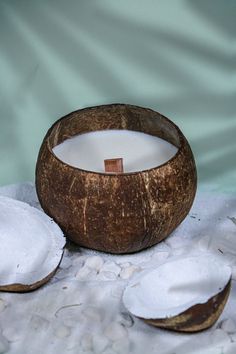 two coconuts and a candle sitting on top of some white sand next to each other