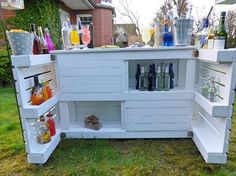 an outdoor bar made out of pallet wood with lots of bottles and glasses on it