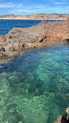 the water is crystal clear and blue with some rocks in it's foreground