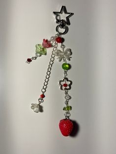 a key chain with charms attached to it's sides and an apple hanging from the end